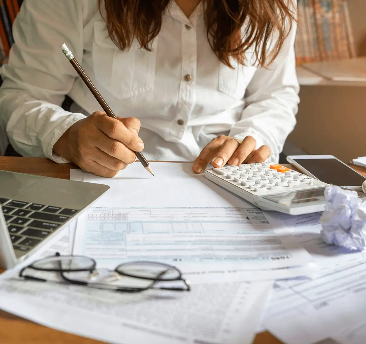 Person calculating expenses with documents and calculator.
